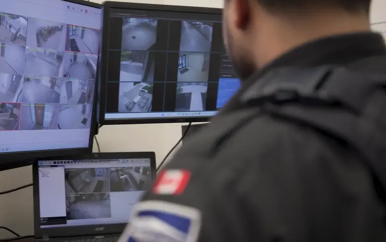 Security guard monitoring surveillance cameras on screens